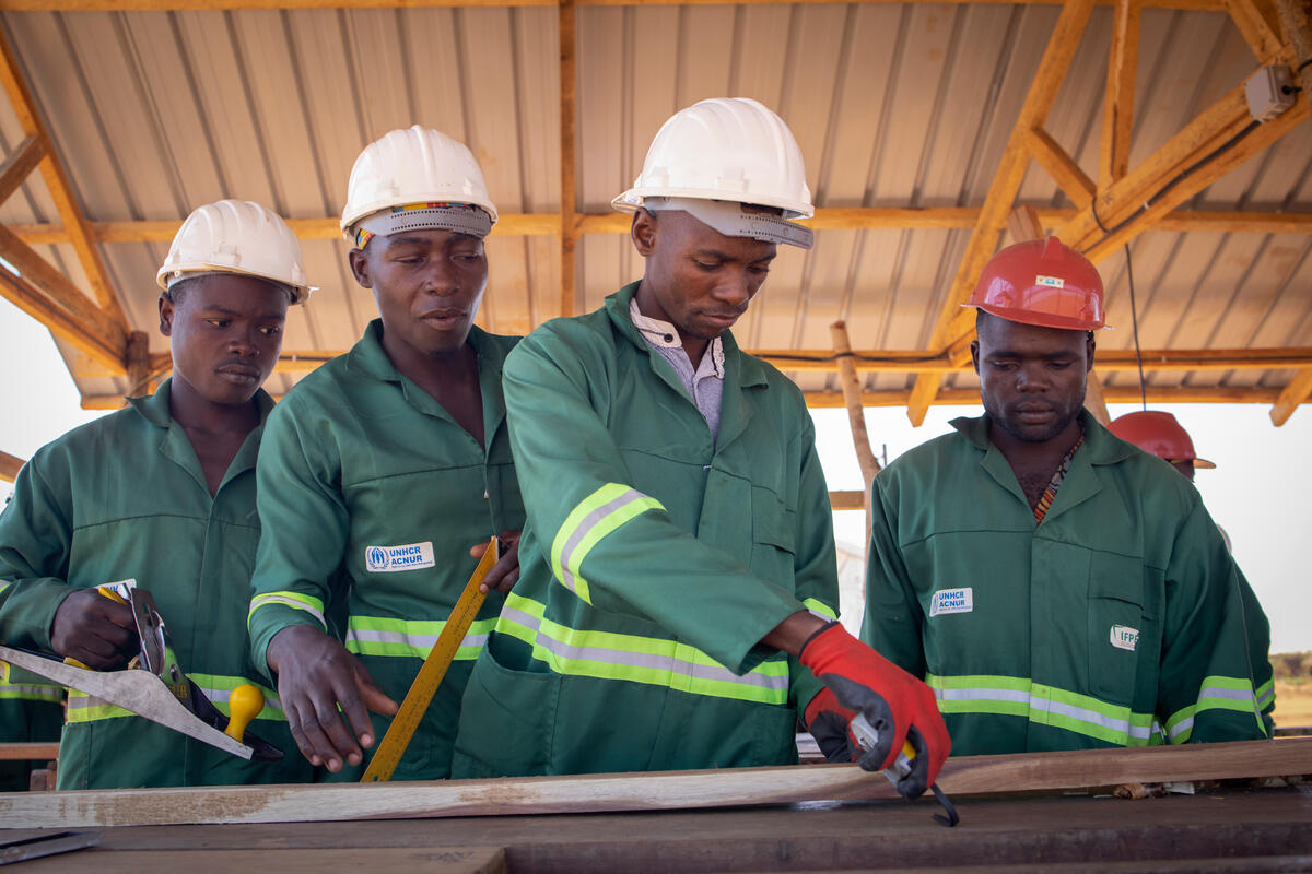 Personas desplazadas internas de Mozambique aprenden a fabricar tablones para construir sus propios alojamientos en el asentamiento de desplazados de Corrane, provincia de Nampula, Mozambique.