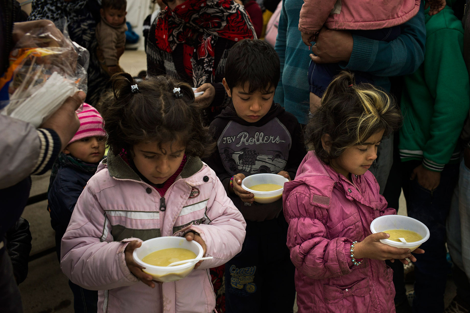 Refugee children are served bowls of hot porridge after disembarking from boats