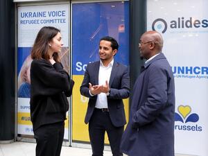 Three members, from Refugee Committees and UNHCR standing and having a conversation in a community centre for refugees in Brussels
