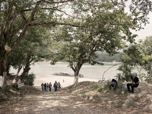 A group of people walk away from a river bank.