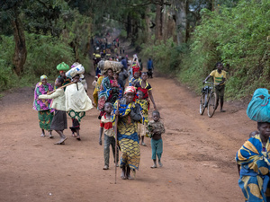A group of displaced people walk along a road carrying their belongings, in the Democratic Republic of Congo.