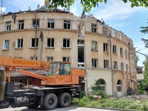 A crane is parked in front of a partially destroyed residential building in Ukraine 