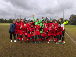 A women's football team gathers for a group portrait on a football field.
