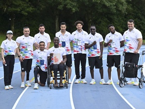 Des athlètes en uniformes assortis posent pour une photo de groupe sur une piste de course.
