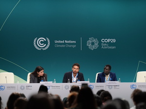 A woman and two men address a session at COP29.