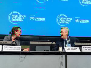 A woman and a man face each other at the podium.