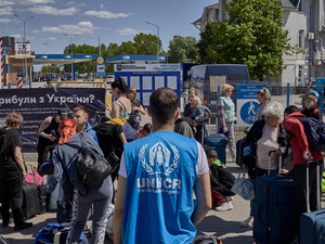 A UNHCR staff member provides assistance to a large group of Ukrainian refugees, who gather with their belongings in Moldova after crossing the border.