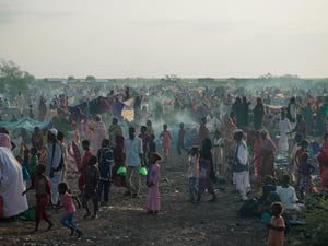 A large number of new arrivals from Sudan wait in a field in South Sudan