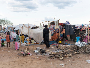 Children walk along a dirt road in a transit centre