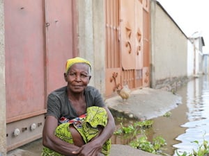 A woman sits on the ground in a flooded neighbourhood.