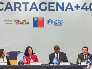 Quatre personnes sont assises à une table avec des microphones lors d'une réunion du processus, avec "Cartagena+40" et divers logos sur le mur derrière eux.