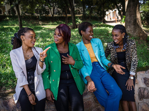 Four women sit together in a park and talk with each other.