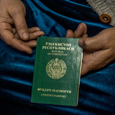 Close up of a woman's hands holding her invalid Uzbeck passport. 