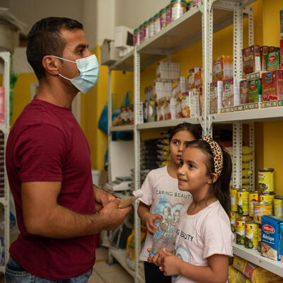 Un homme et ses deux filles choisissent des produits alimentaires dans une petite épicerie.