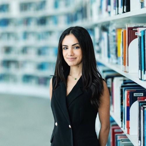 Rooan Alkalmashi stands smiling in a library