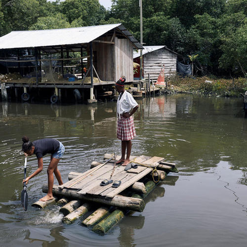 كولومبيا. فتيات يعبرن قناة أشجار المانغروف في قارب يدوي الصنع.