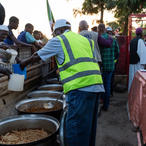 Volunteers serve food at an outdoor community kitchen in Omdurman