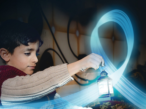 A young boy is holding a small lantern in a dark room. A blue, shiny and flying ribbon floats around the lantern.