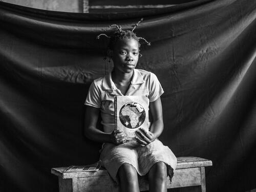 Thirteen–year-old Fideline holds one of the school notebooks that she was able to salvage when she and her family fled for their lives and boarded a boat to Batanga.