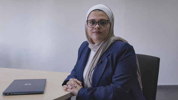 Zeina Hyari, assise à un bureau avec un ordinateur portable fermé, regardant la caméra.