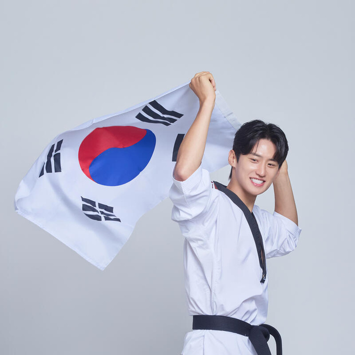 Daehoon Lee waves a Korean flag while wearing a taekwondo uniform