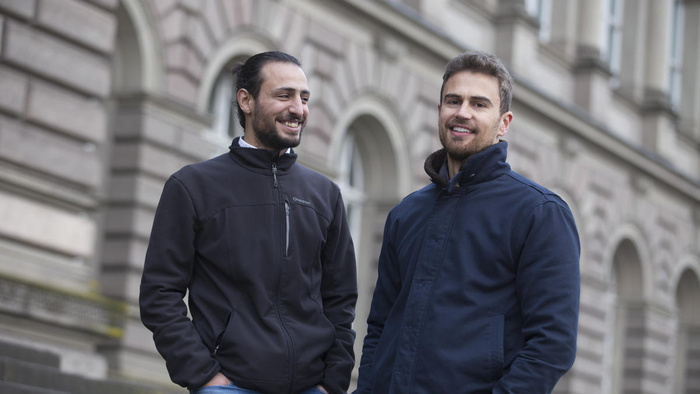 Two men stand next to each other and laugh
