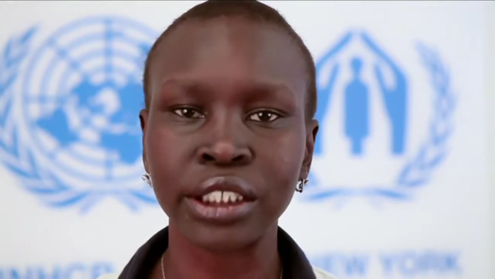 Alek Wek speaking in front of the UNHCR and UN flags