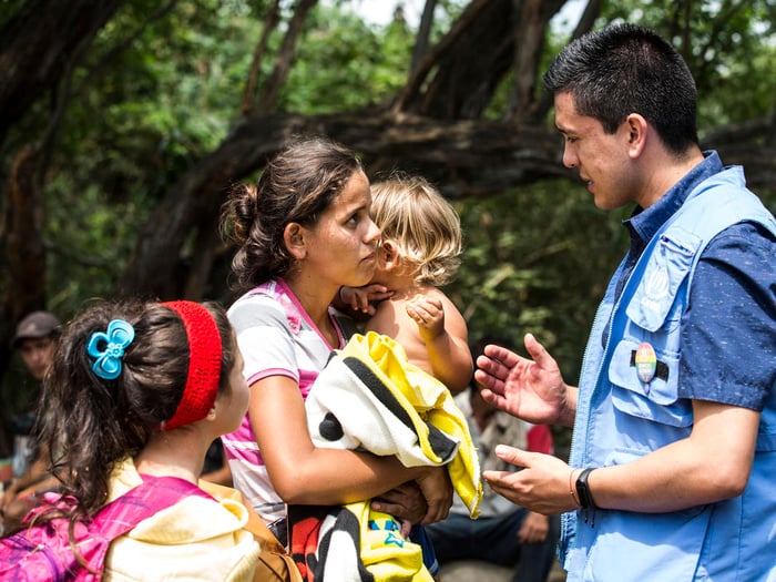 A woman with two young children speaks with a UNHCR staff member, in Colombia.