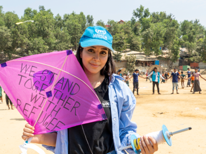 Aseel Omran holding a pink kite reading "We stand together with refugees"