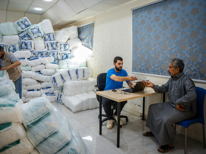Three men are in a room used to stock diapers.