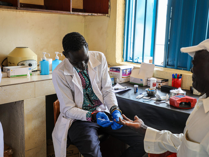 South Sudan. Manamanyi Ojulu, one of the lab technicians at Gorom Primary Health Care Center, administering Malaria Rapid Diagnostic Test