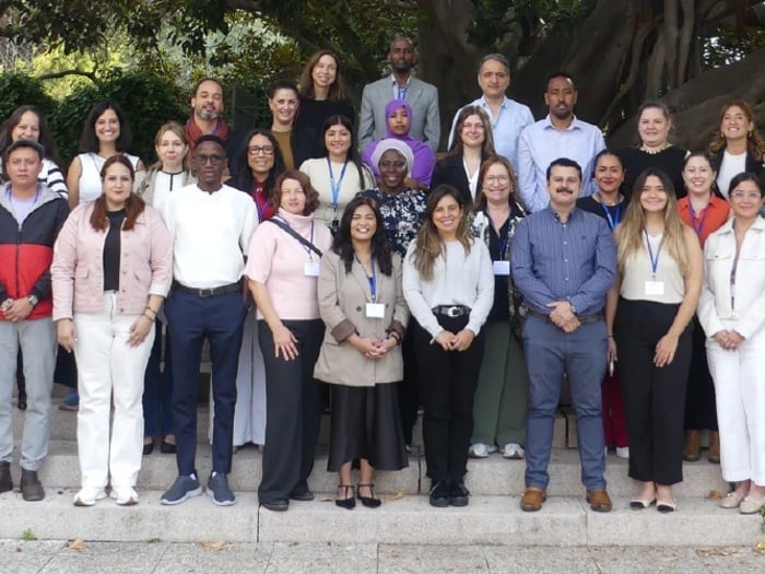 A large group of people pose for a photo on some steps under some large trees