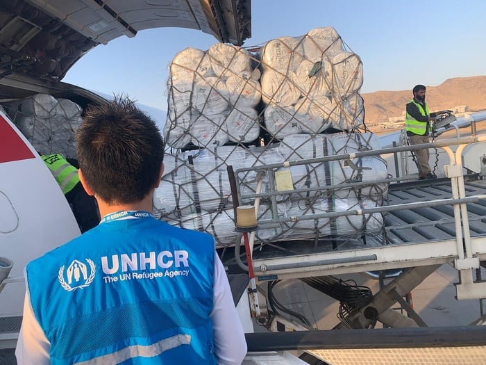 A UNHCR staff member oversees an airlift's landing, carrying humanitarian assistance.