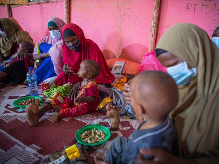 Mothers and children sit in a circle and share a meal during an Infant and Young Child Feeding counselling session.