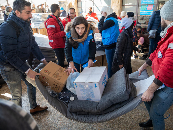 UNHCR staff members and other persons carry blankets and relief items.