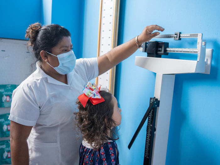 A refugee girl in Guatemala has her height and weight measured at a health facilty as part of a check up. 