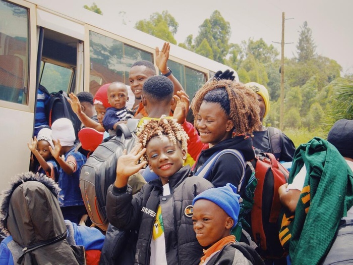 Families smile and wave as they board a bus