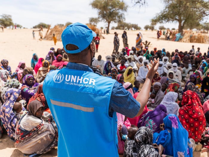 A UNHCR staff member is pictured from behind addressing a group of Sudanese refugees.