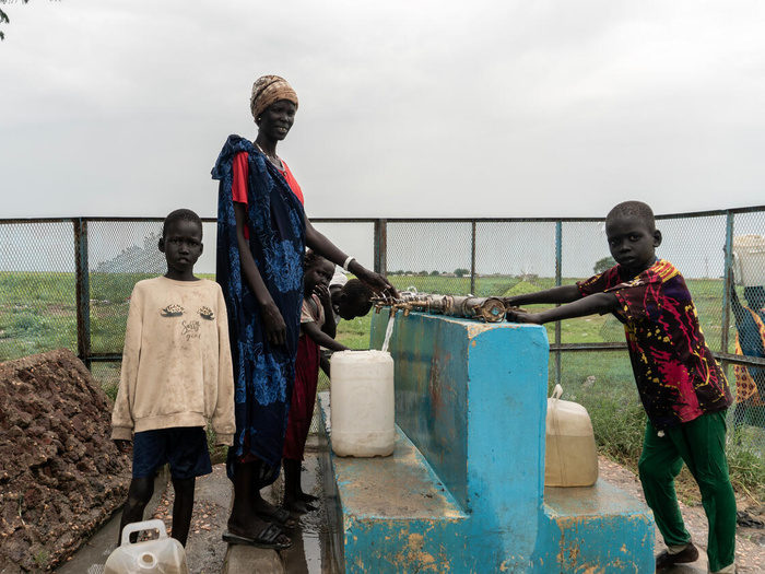 Refugees gather water via a solar-powered water system.