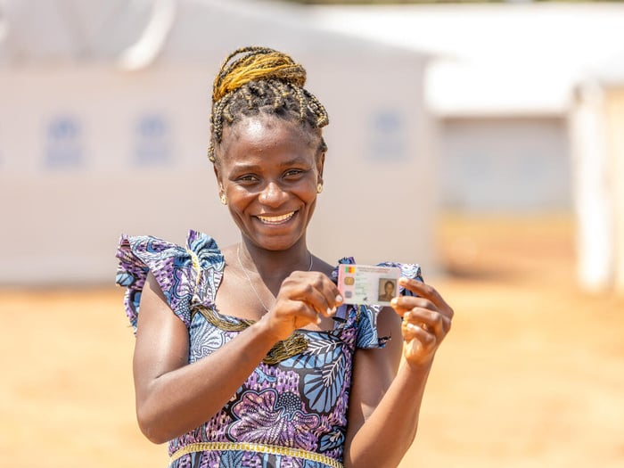 A Central African woman smiles proudly and holds up her national ID card