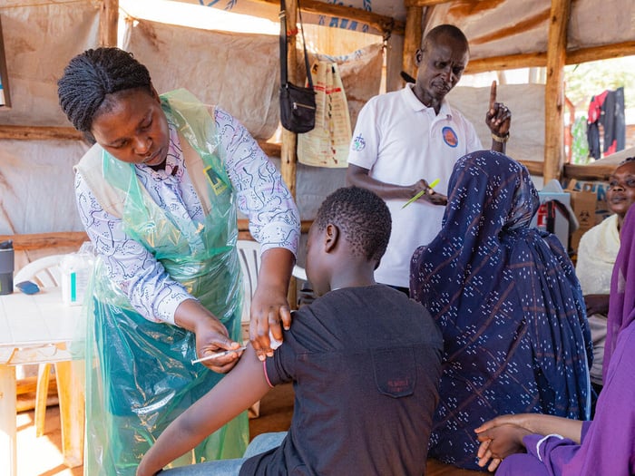 Several people receive vaccinations and other medical consultation in a makeshift shelter outdoors