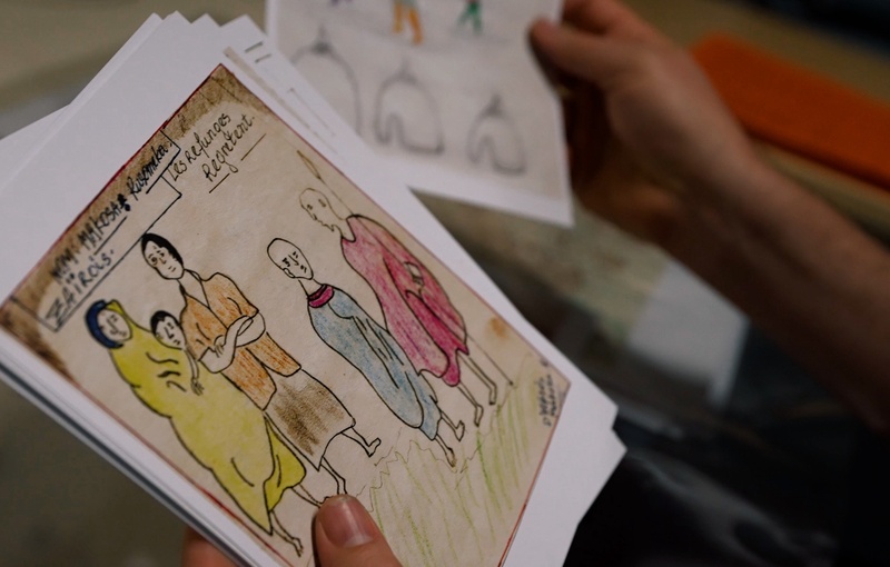 Close up of a person holding children's drawings of colourful figures