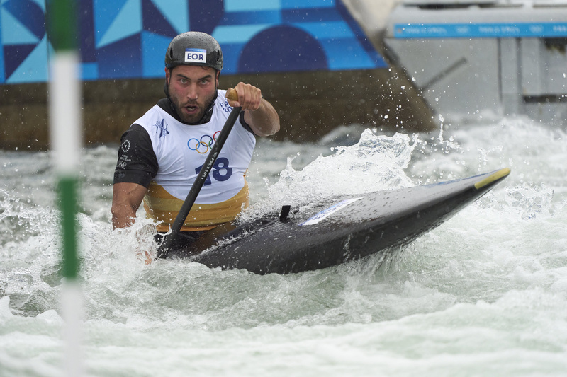 Amir, portant un casque et un dossard olympique, dirige un canoë pendant une course.