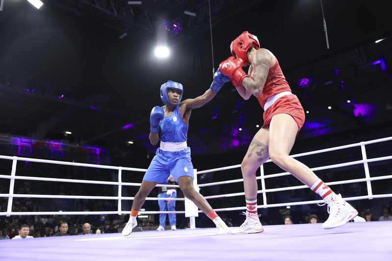 Une femme habillée en bleu se bat avec une femme habillée en rouge sur un ring de boxe.