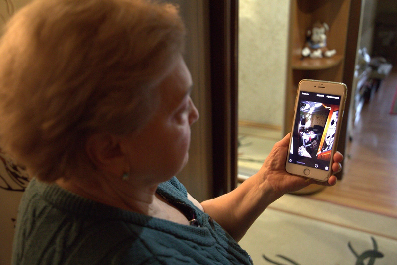 Une femme brandit un téléphone portable montrant une photo de l'intérieur endommagé d'un appartement.