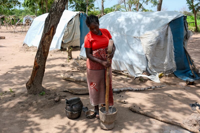 Une femme avec un poteau en bois, un seau en bois et quelques pots à l'extérieur d'un abri de fortune