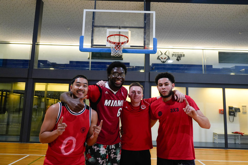Quatre hommes se tenant par le bras sur un terrain de basket-ball