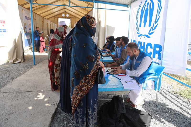 A woman speaks to a UNHCR staff member at a desk in the Kabul Encashment Centre, Afghanistan.