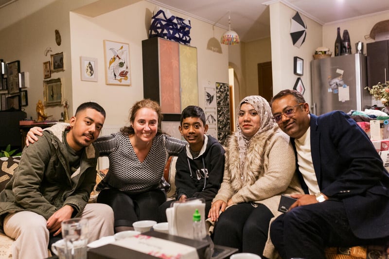 A Rohingya refugee family poses with a friend in her living room.