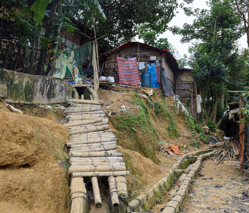 An uneven bamboo path on a hillside in a camp that has been eroded by monsoon rains.